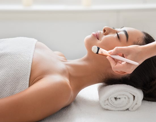 Relaxed asian woman enjoying beauty treatments in spa centre, waiting for beautician to apply facial clay mask, having wellness day at parlor, lying on massage table with closed eyes, side view